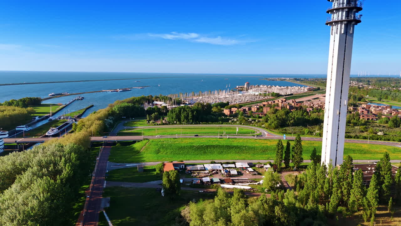Footage over the scenery approaching telecom tower in Lelystad, the Netherlands. Amazing marina with a yacht club at backdrop. Aerial perspective.