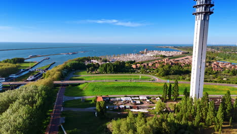 footage over the scenery approaching telecom tower in lelystad, the netherlands. amazing marina with a yacht club at backdrop. aerial perspective.
