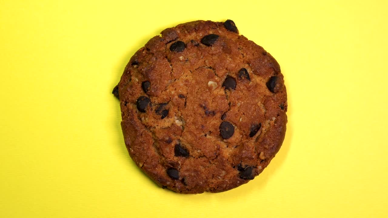 una galleta de chocolate en primer plano, una foto macro, girando rápidamente sobre un fondo amarillo giratorio.