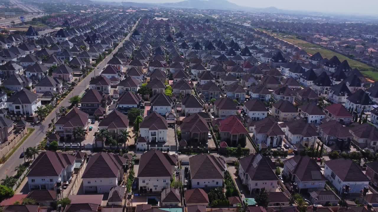 Pemandangan deretan panjang rumah-rumah mewah berukuran besar di lingkungan pinggir kota yang baru dibangun di Abuja, Nigeria pada hari yang cerah.
