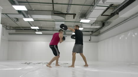 kick boxer cumple con el entrenador las laderas de la udra y las inmersiones en las patas en cámara lenta.