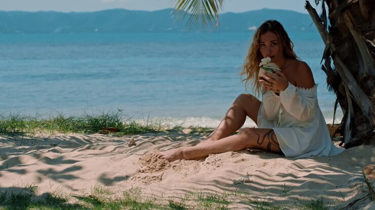 Woman drinking coconut on beach