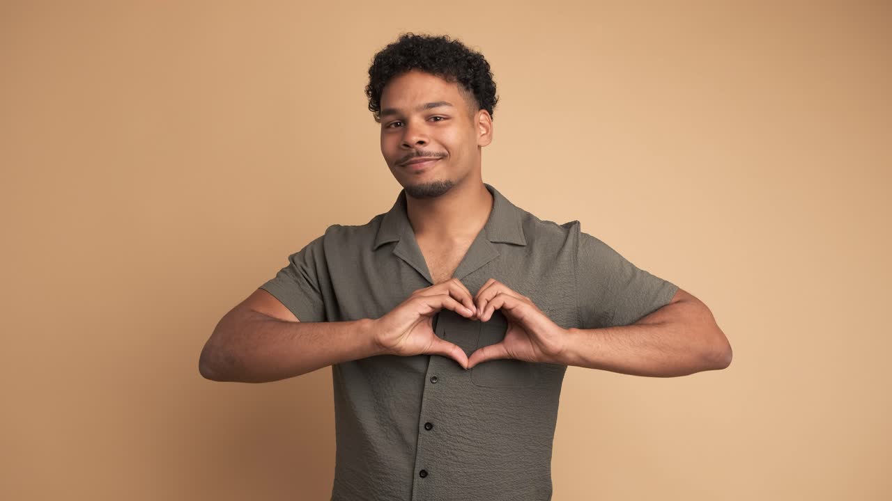 Uomo allegro che fa il segno del cuore con le mani per mostrare affetto