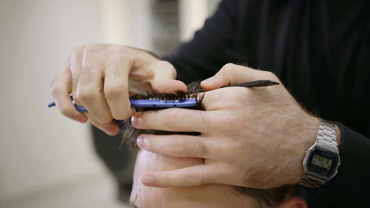 Nærbillede af en barber, der klipper en mands hår