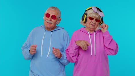 senior stylish grandparents pensioners listening music via headphones, dancing disco fooling around