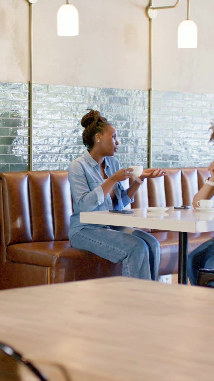 Video verticale: Sentire il compagno parlare, donna in jeans che si appoggia e solleva una tazza al caffè con il telefono