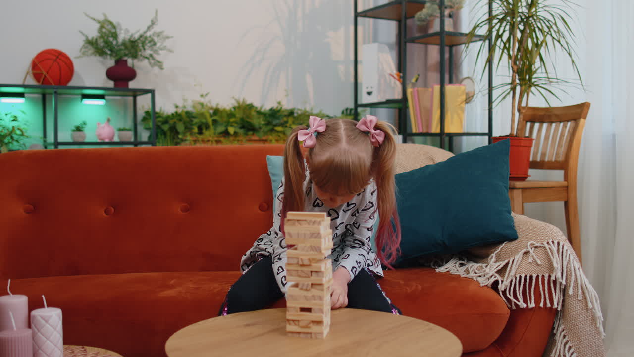 Simpatica ragazzina gioca con un gioco di costruzioni a torre in legno a casa in un moderno soggiorno