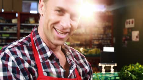 smiling male staff arranging fresh vegetables in basket