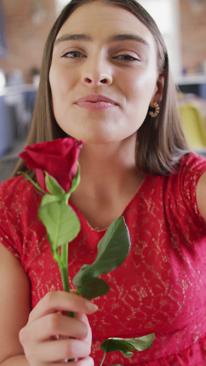 video vertical de una mujer caucásica sonriente sosteniendo una rosa roja haciendo una llamada de video del día de san valentín