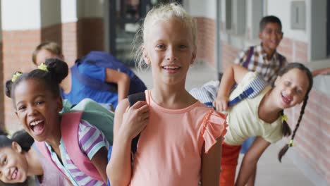 Video-of-happy-caucasian-girl-and-diverse-pupils-at-schoot-corridor