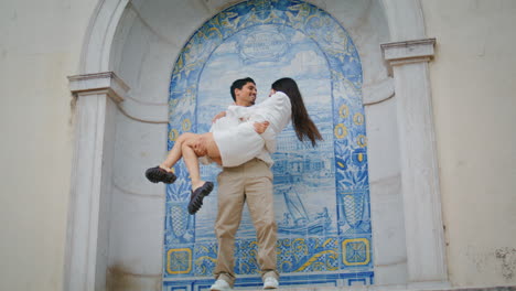 enamoured sweethearts embracing ceramic tile place. man carrying woman at hands