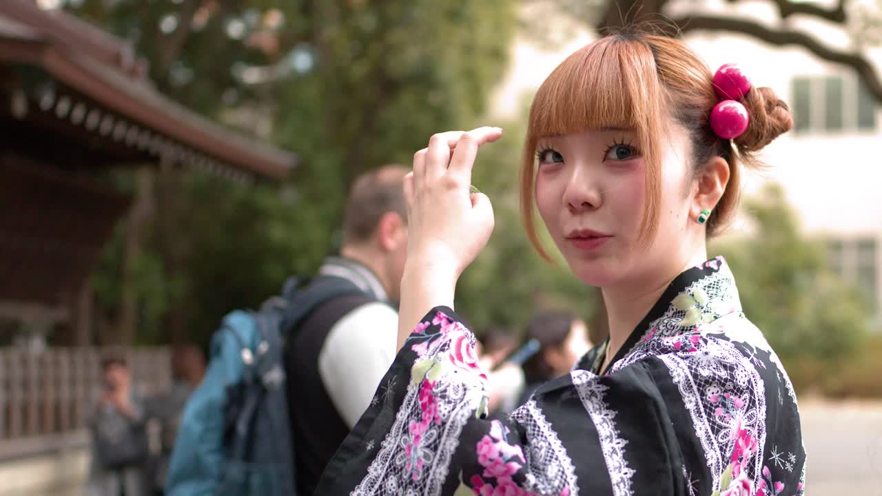 Una giovane donna che indossa un yukata tradizionale si sistema i capelli mentre visita un tempio shintoista.