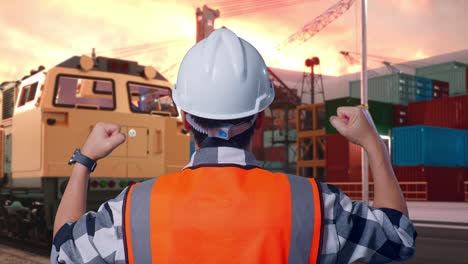 engineer celebrating success at port with train and containers