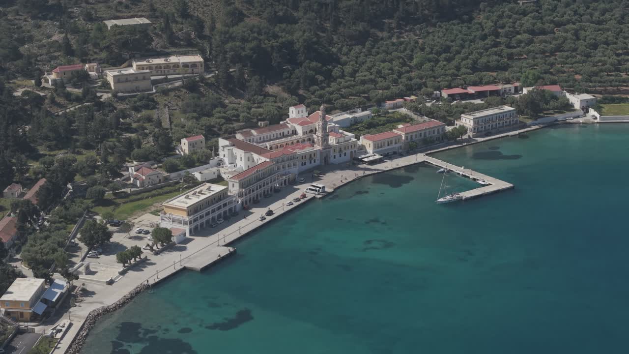 Wide Cinematic drone shots revealing the sacred grounds of Archangel Michael Monastery at Panormitis bay. The aerial view captures the monastery's peaceful setting surrounded by pristine waters.