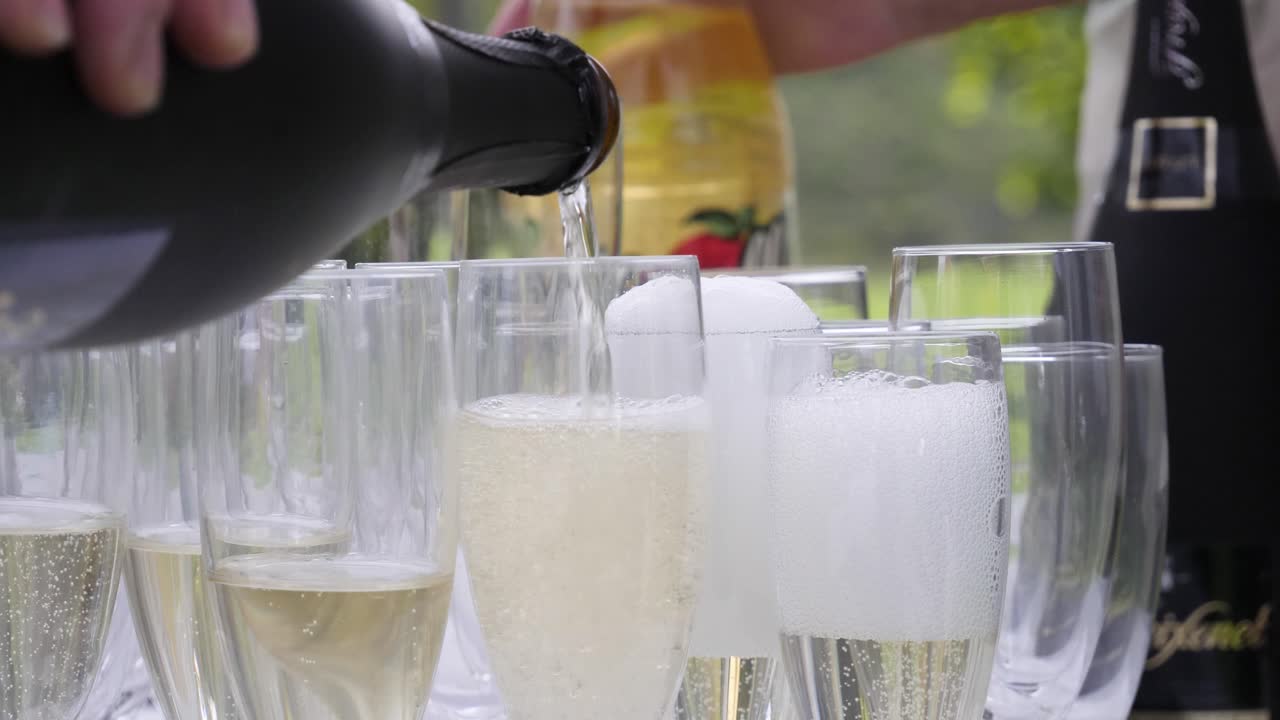 Champagne versato in bicchieri di cristallo durante una grande celebrazione all'aperto, come un matrimonio o un anniversario