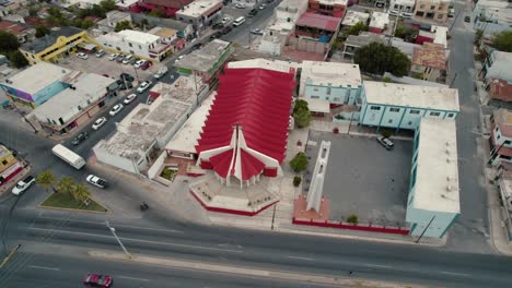 Aerial-over-church-San-Pío-X-at-Reynosa,-Tamaulipas,-road-with-traffic-near-by,-video-sequence-promoting-religious-and-spirituality-concept