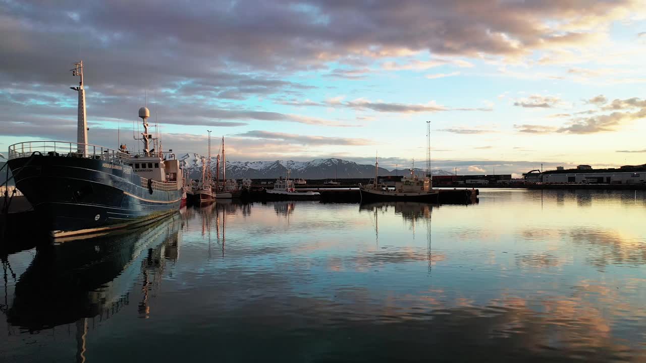 вид с воздуха на традиционные рыбацкие лодки, стоящие в гавани в красивом городе хусавик, залив скьяльфанди, исландия - съемка с дрона
