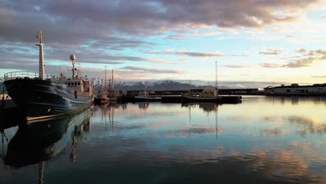 Vista-Aérea-De-Los-Tradicionales-Barcos-De-Pescadores-Que-Se-Encuentran-En-El-Puerto-De-La-Hermosa-Ciudad-De-Husavik,-Bahía-De-Skjalfandi,-Islandia---Disparo-De-Drones