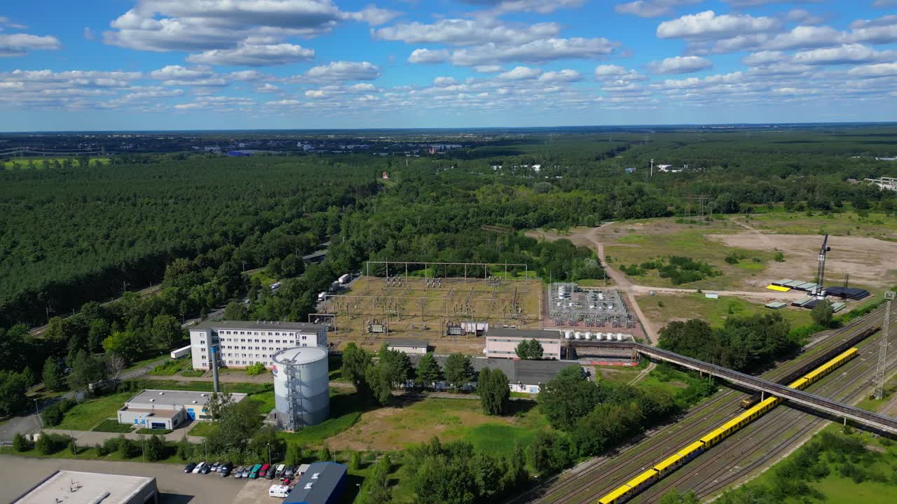 Hennigsdorf substation, distributing electricity and surrounded by a lush green forest in Brandenburg, Germany. Unique aerial view flight panorama orbit drone