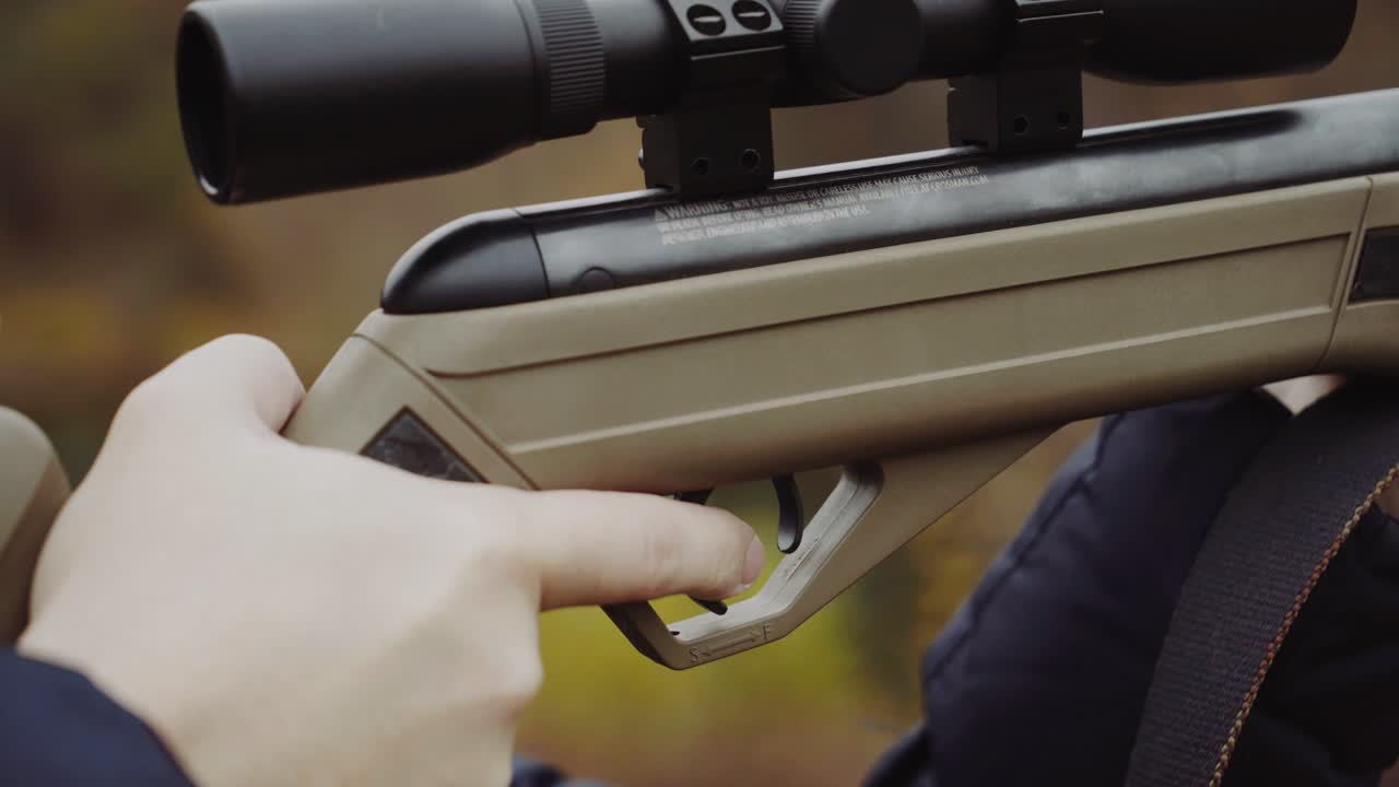 Man shooting gun in forest. Close up of male hunter in the forest aiming and shooting with hunting rifle