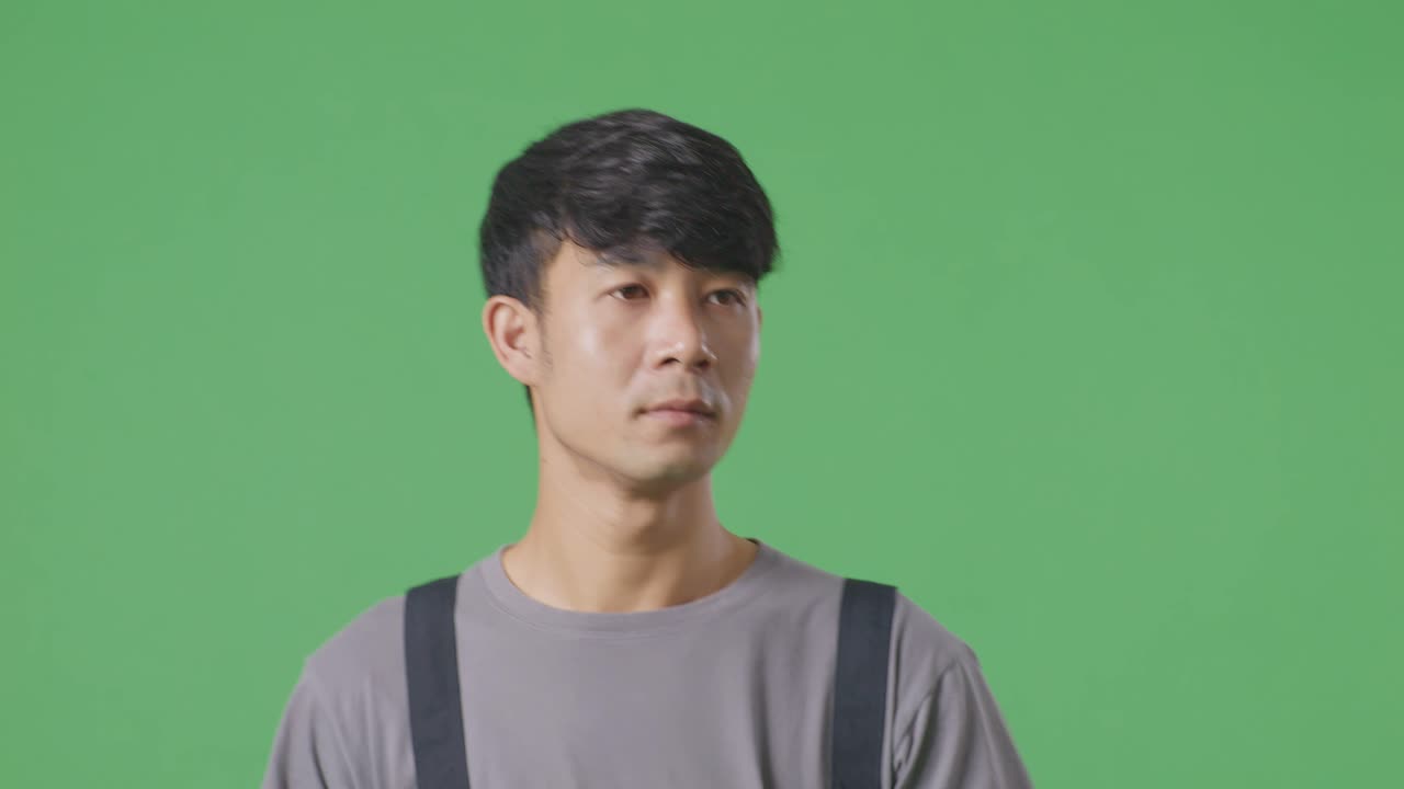 녹색 스크린 배경 스튜디오에서 걸어다니고 둘러보는 아시아인 노동자의 클로즈업