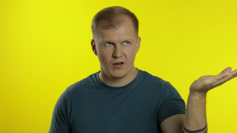 portrait of young caucasian man posing in t-shirt. dissatisfied guy puts hand on face, facepalm