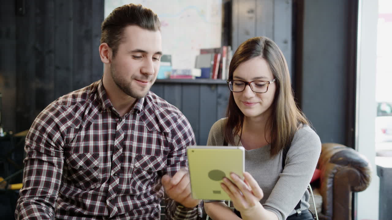 una pareja joven revisando la tableta juntos.