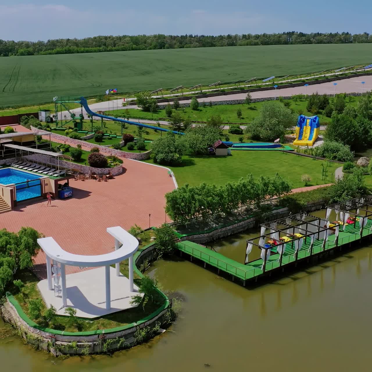 Modern recreation complex near the river. Park with relaxing area on the background of nature in summer. Aerial view.