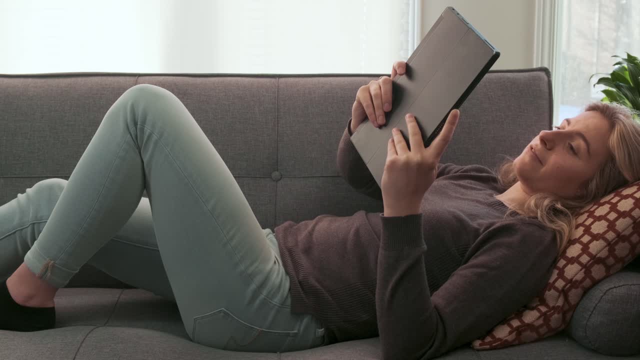 Slider shot of a young woman on a video call using her tablet