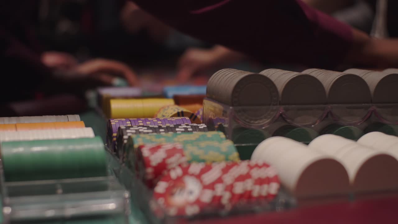 Rack focus from poker roulette chips to group of people placing chips on table board in slow motion
