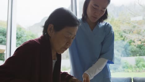 smiling asian female doctor helping senior female patient to walk using walking frame