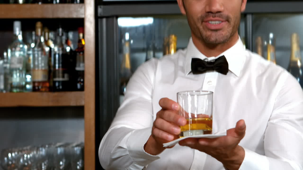 Barman sorridente che serve un whisky
