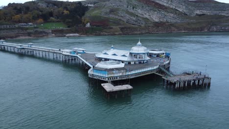 Llandudno-pier-historic-Victorian-wooden-boardwalk-seaside-landmark-aerial-view-orbit-right-from-side-pavilion