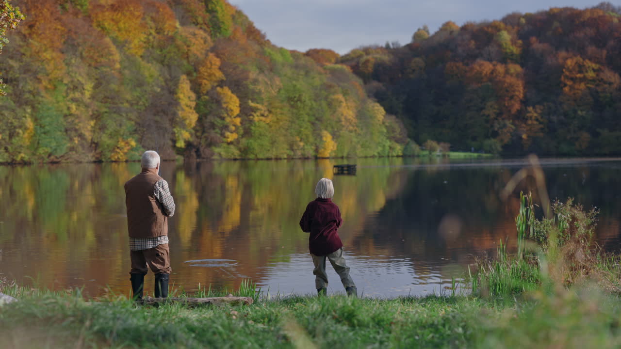 Grandfather and Grandson Fishing by a Lake in Autumn