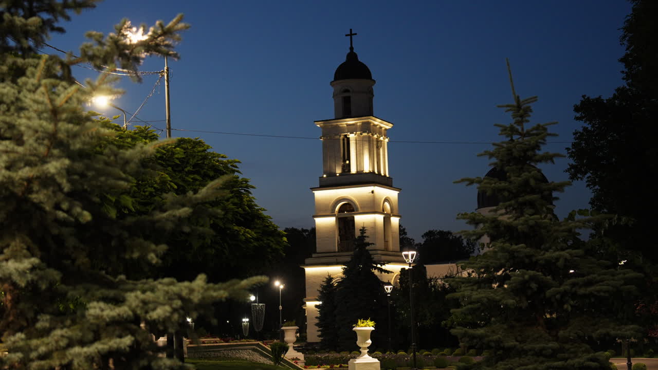 Chișinău Cathedral Bell Tower at dusk with trees in the foreground. Quiet evening atmosphere in the central park area of Moldova’s capital.