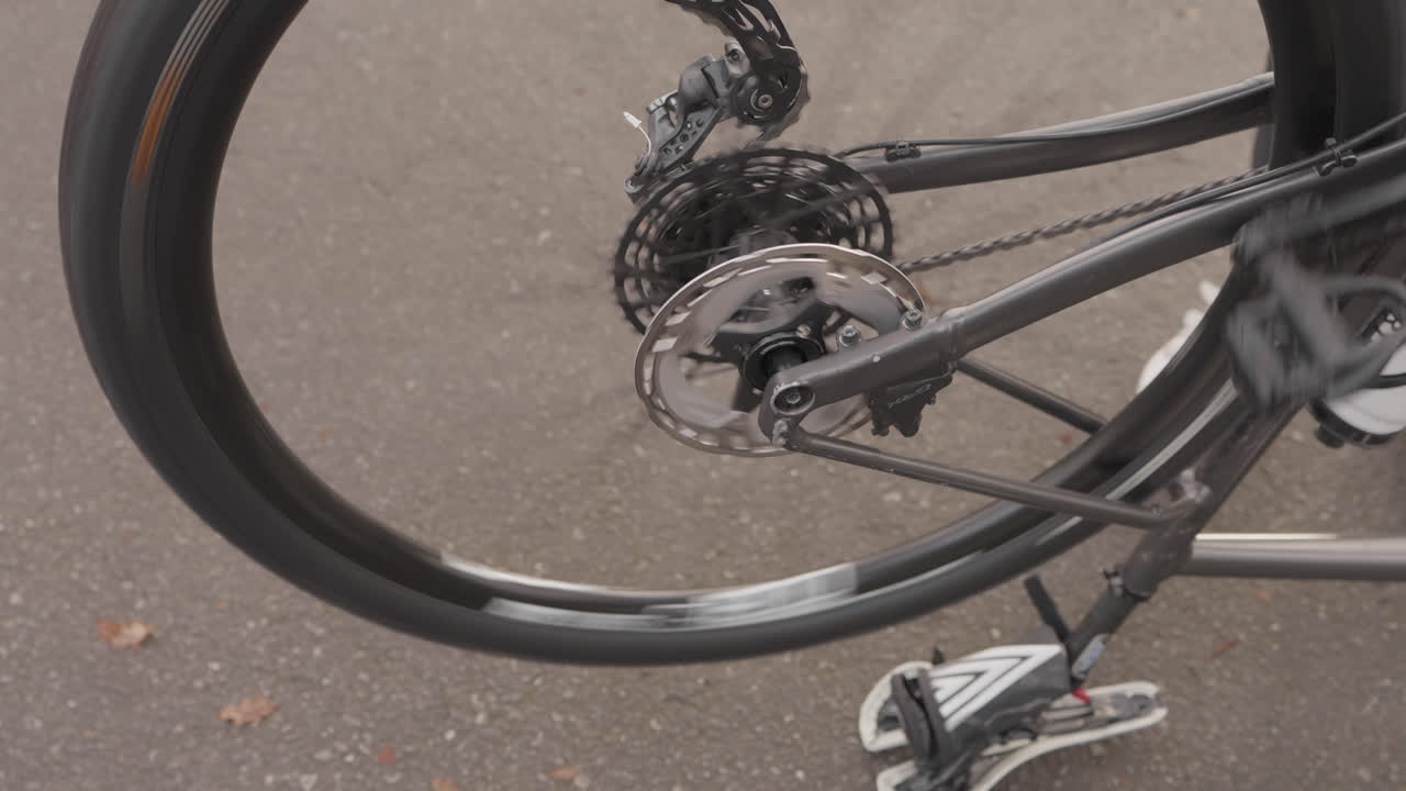 Close-up de corrente da cassete de bicicleta de estrada e roda traseira girando no pavimento