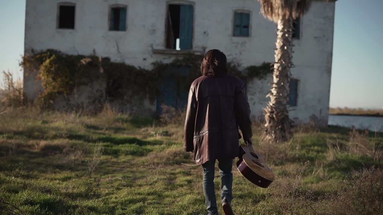 Man Walking With Guitar in Front of an Abandoned House