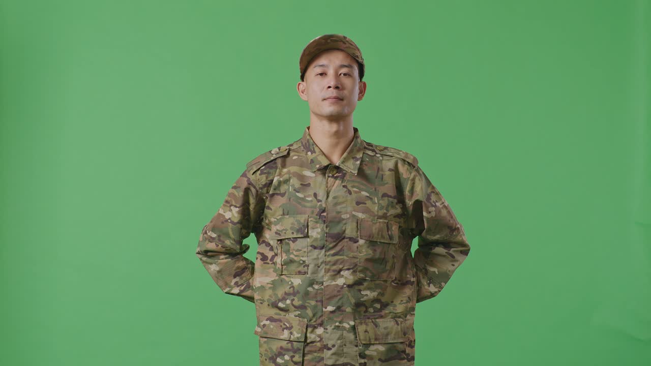 Asian Army Soldier Standing Against On Green Screen Background Studio. Brave Young Servicemen Wearing Camouflage Military Uniform