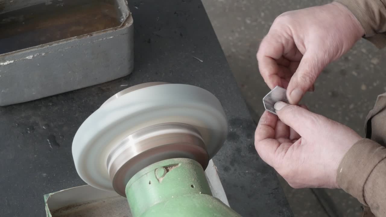 은 손의 마스터는 벤치 그린더, 거친 그린더 머신, 클로즈업, 피데스탈 그린더 작업, 물건 생산, 공장에서 금속 부품을 마무리 는 작업을 수행합니다.