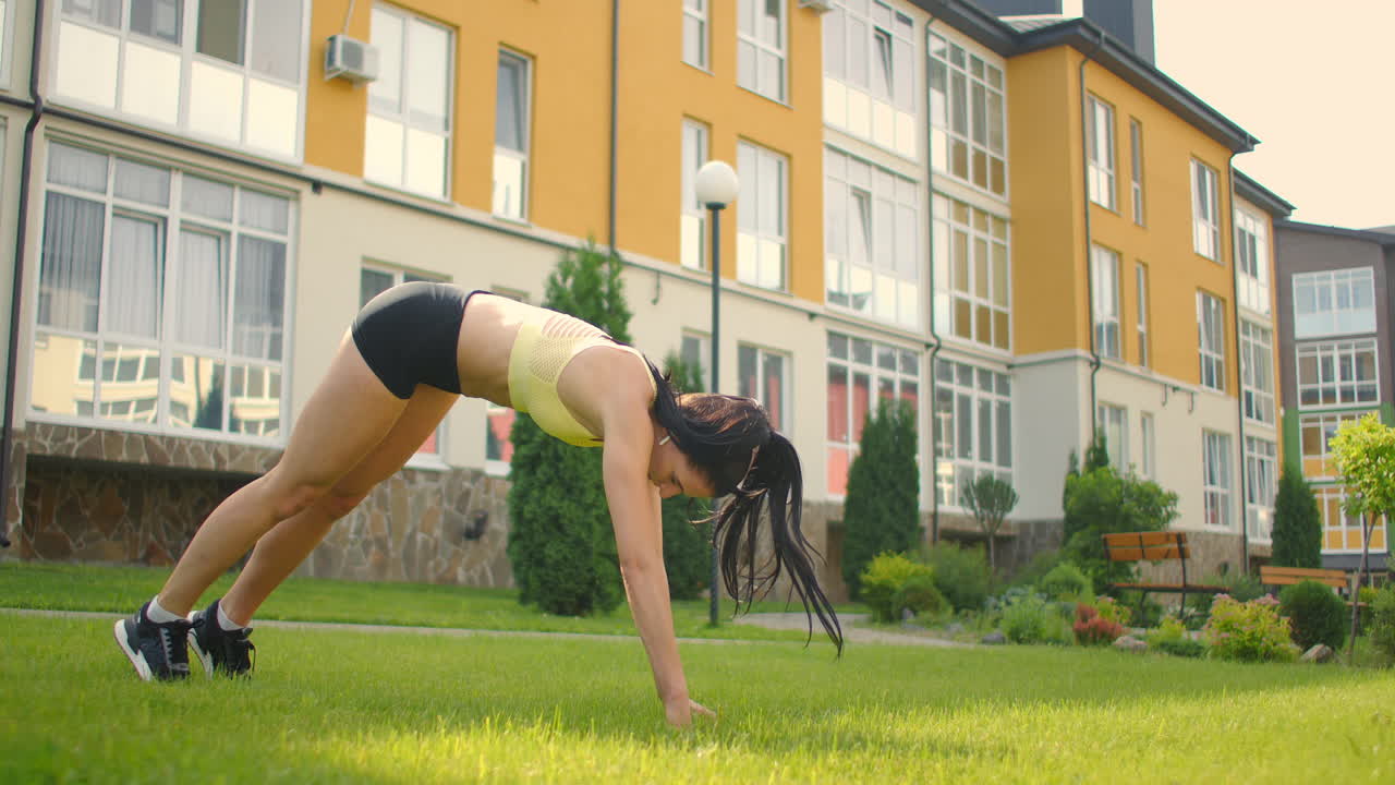 restaurando la fuerza después del entrenamiento. una mujer con auriculares se calienta antes de entrenar en el parque. estirándose al aire libre.