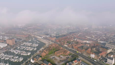 Vuelo-Aéreo-Sobre-El-Centro-Del-Casco-En-Un-Día-De-Niebla-Que-Revela-El-Puerto-Deportivo