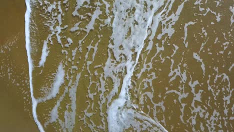 foam patterns on the sand become into bubbles and melt foam white patterns of waves on the yellow wet sand become into bubbles and melt aerial survey