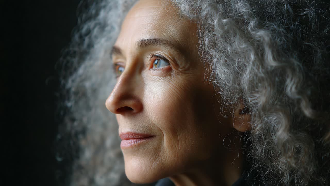 Capturing Serene Reflection: A Beautiful Close-Up of a Graceful Woman with Silvery Curly Hair in Soft Natural Light, Emphasizing Peace and Contemplation