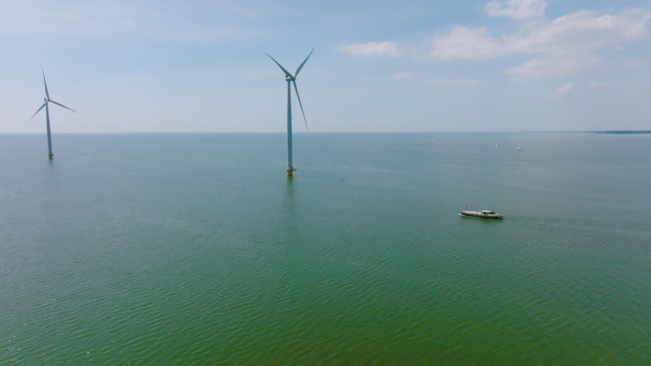 A traveling ship sails under wind turbines in the North Sea