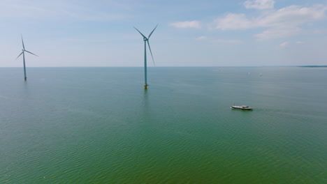a traveling ship sails under wind turbines in the north sea