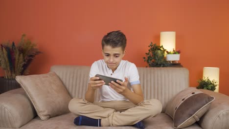 el chico juega juegos en el teléfono en casa.