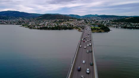 Drone-view-of-a-busy-bridge-with-cityscape-at-background