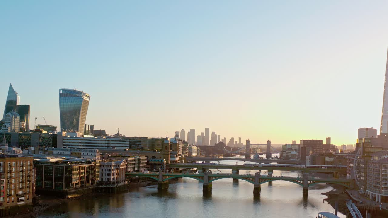 일출 시 카나리 워프를 향해 템즈강 교량을 가로지르는 공중 상승 드론