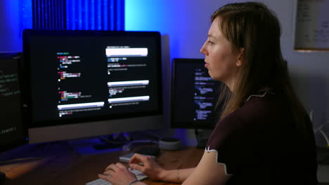 Young artificial intelligence computer code programmer working in a programming office with multiple screens