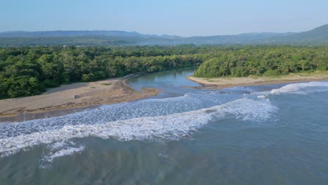 Aerial-view-of-mouth-of-river-connecting-Munoz-River-and-Caribbean-sea-surrounded-by-green-island---Dominican-Republic-in-summer